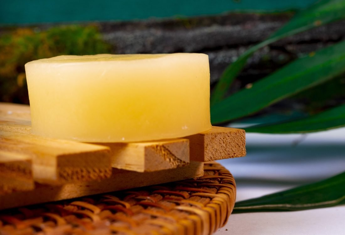CAD_3572 – Copia Condicionador sólido Hapó Natural sobre um suporte sustentável com um fundo verde simulando um ambiente natural.